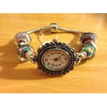 Quartz watch with snap closure. Teal beads with pink flowers, purple glass with white stripes, black and white spacers with crystal accents